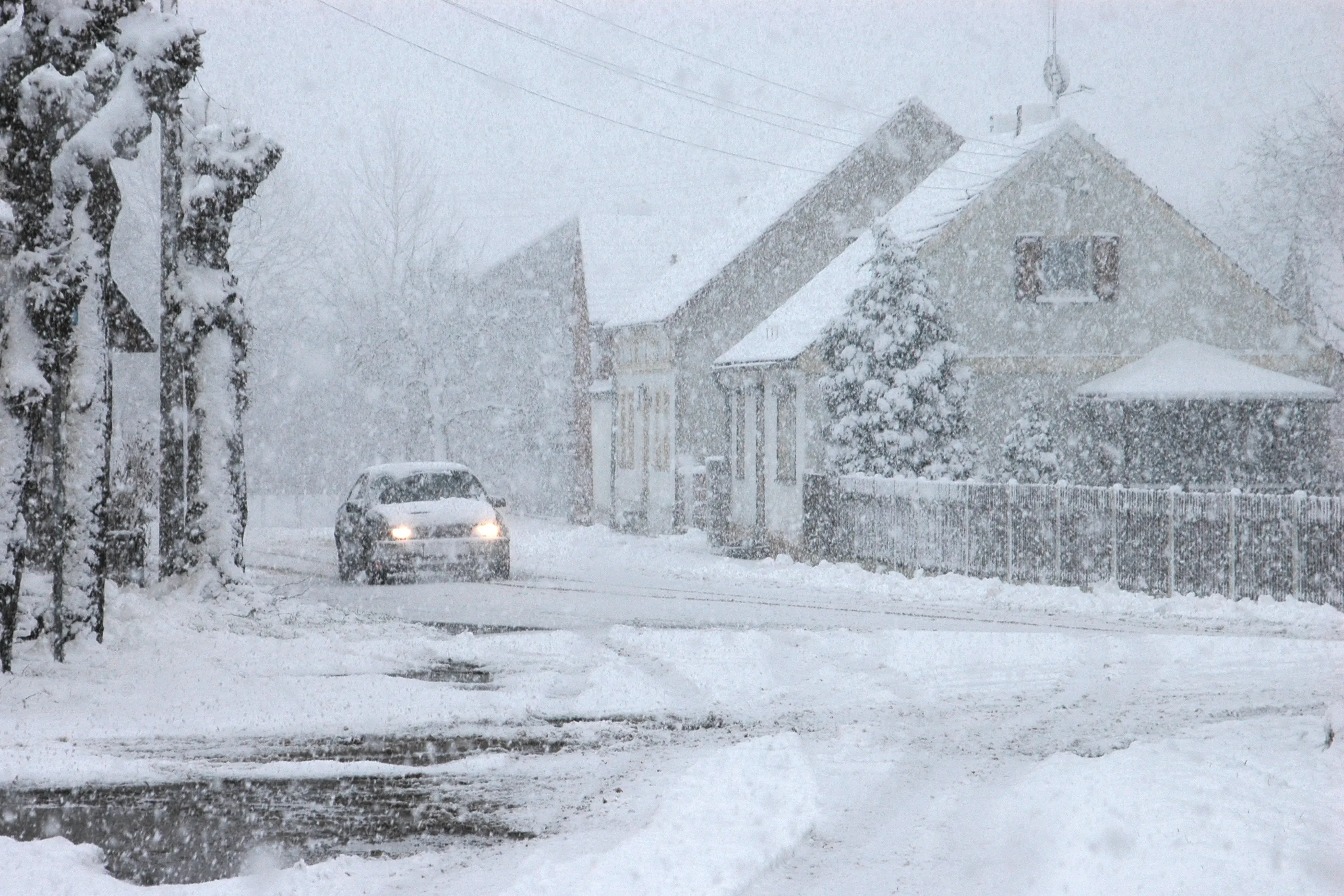 Een auto in de sneeuw in een ondergesneeuwde woonwijk